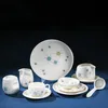 Photographed against a dark blue background is a studio image of a set of cream-colored ceramic dishware bearing a pattern of star-shapes in blue, yellow, and green. There are several pieces, including a platter, a gravy boat with a ladle, a creamer and s