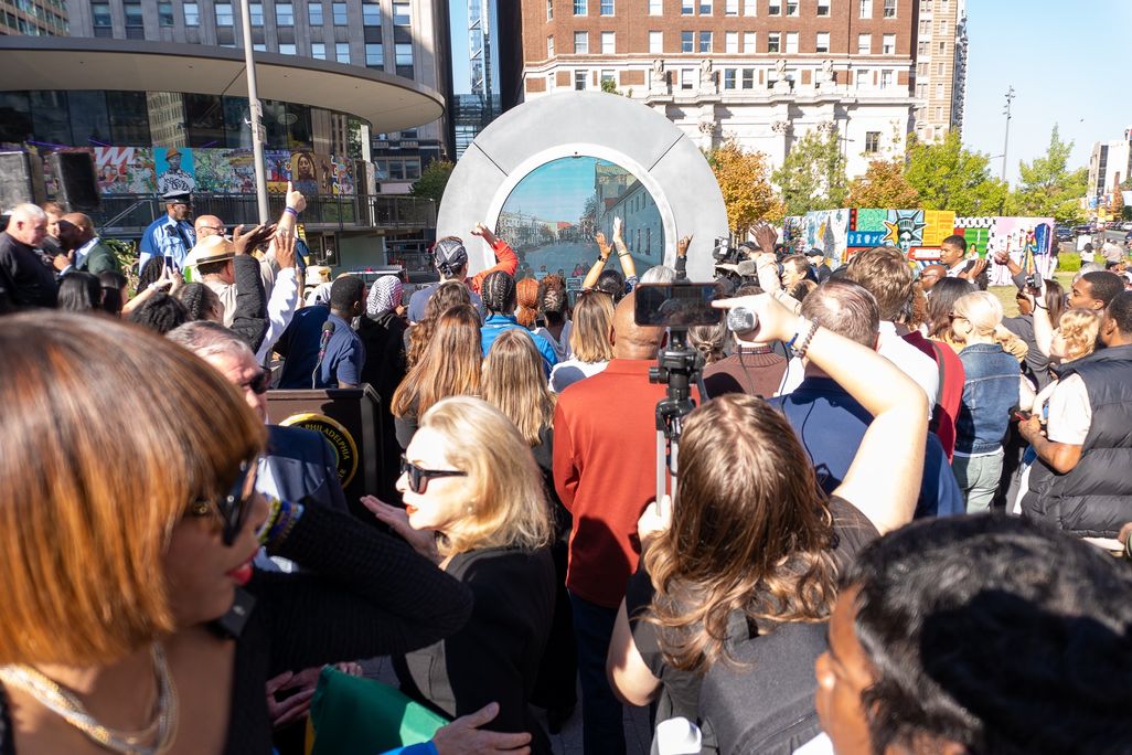 A crowd in front of a portal sculpture