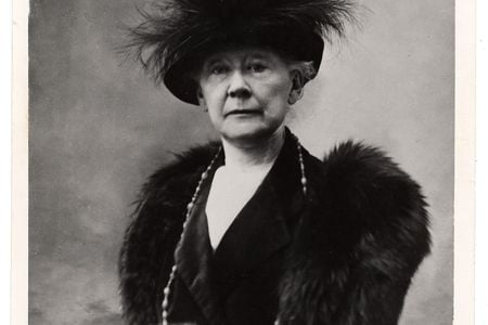 Black and white portrait of Mary Cassatt sitting in a chair wearing fur and a feathered hat.